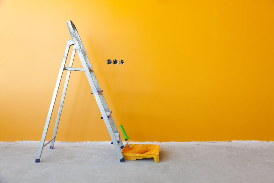 pared amarilla con escalera y cosas de pintar