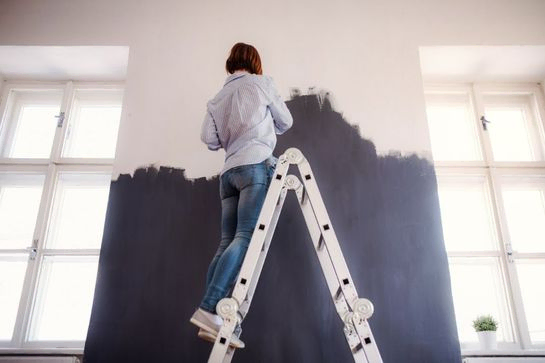 mujer pintando una pared en una escalera